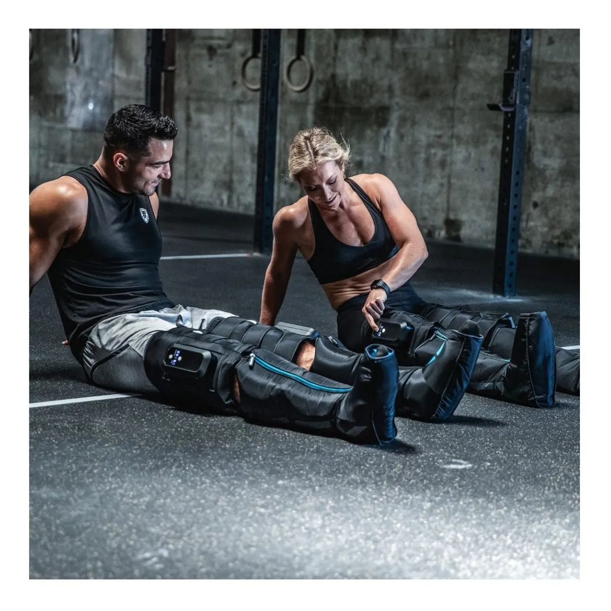 Pareja de atletas usando botas Compex Ayre en gimnasio